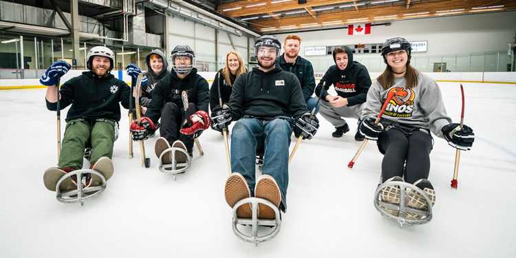 A group of people having fun playing sledge hockey